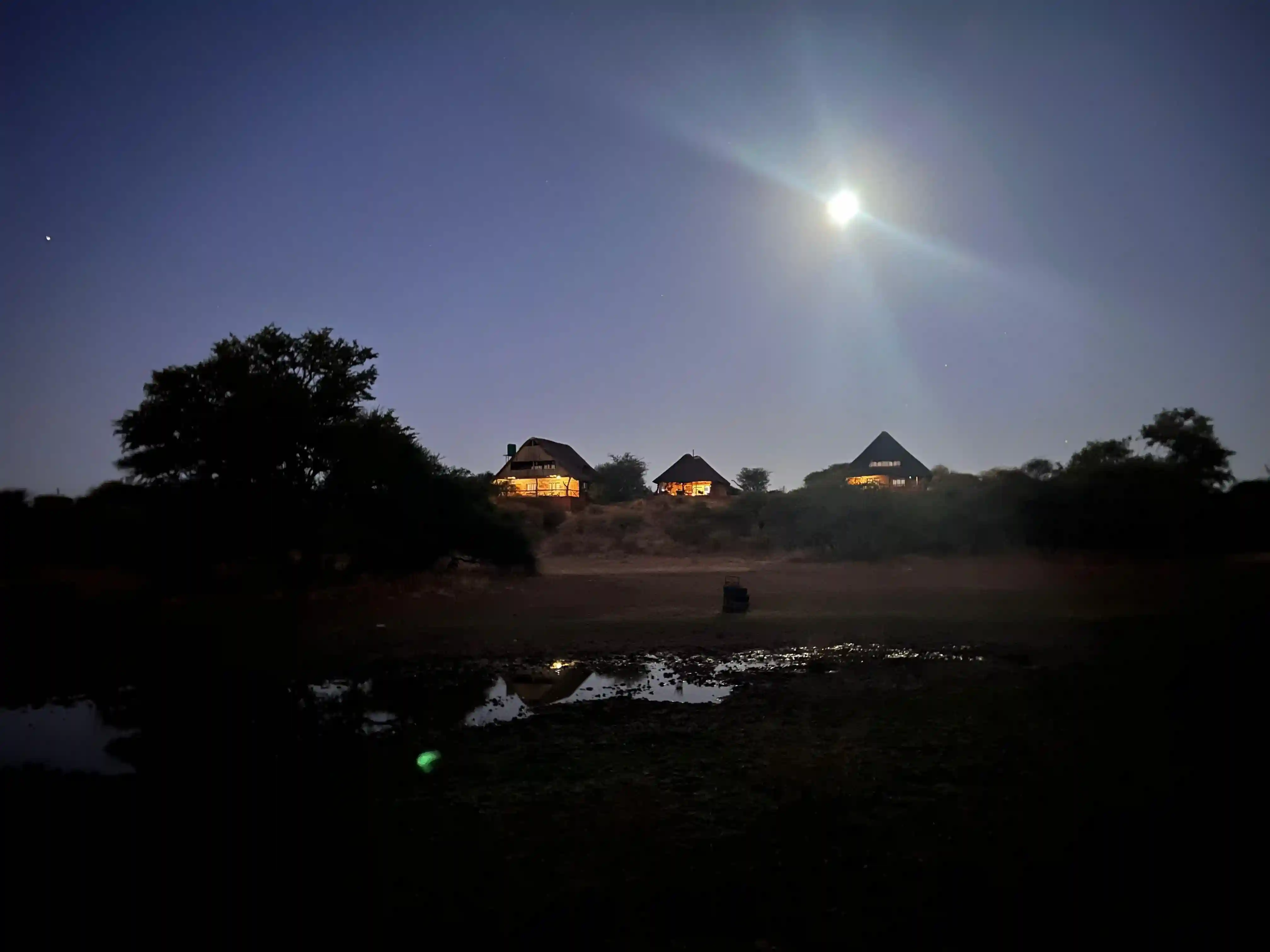 ntorno natural del lodge al atardecer, con edificios de estilo africano rodeados de naturaleza y total tranquilidad.